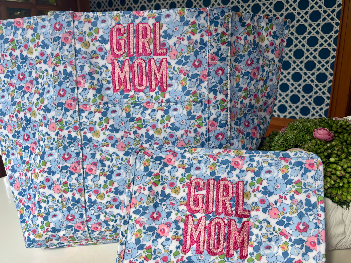Floral-patterned pillows with 'Girl Mom' text on a polka dot wall background