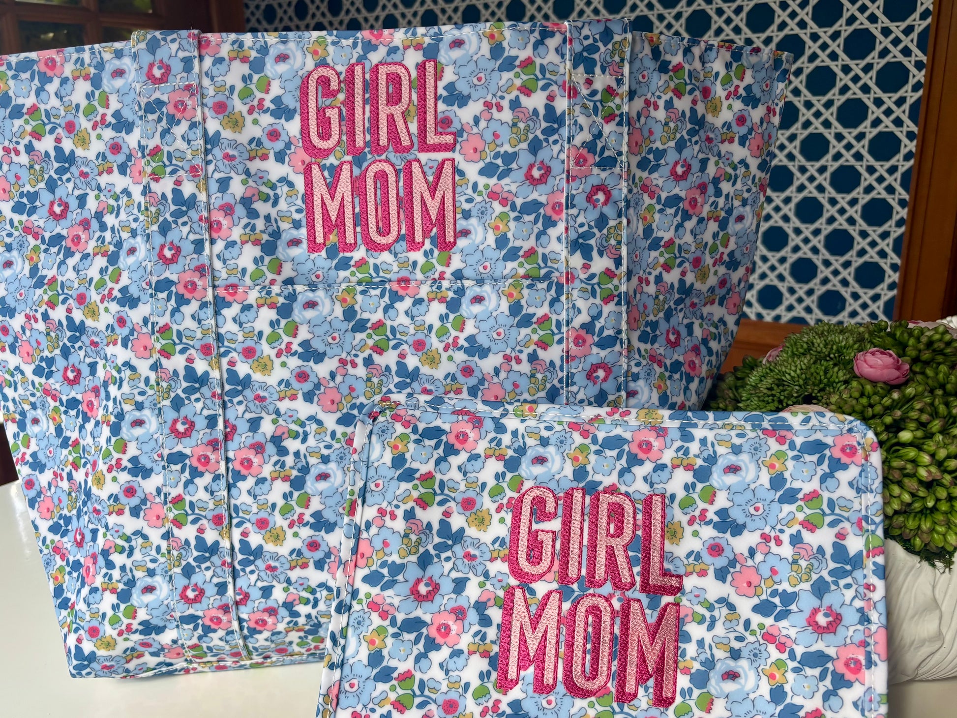 Floral-patterned pillows with 'Girl Mom' text on a polka dot wall background
